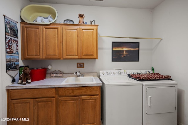 laundry room featuring cabinets, sink, and separate washer and dryer