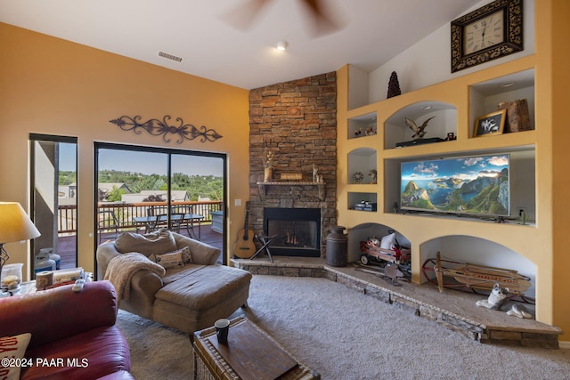 living room featuring ceiling fan, vaulted ceiling, built in features, and a stone fireplace