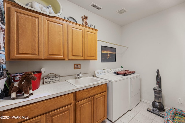 washroom with cabinets, sink, light tile patterned floors, and washing machine and clothes dryer