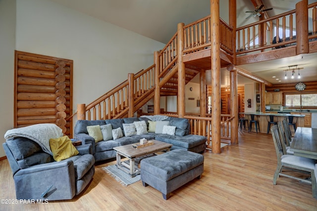 1070 Quiet Pines Ln, Prescott, AZ 86303 - living room with high vaulted ceiling, light wood-style flooring, log walls, a ceiling fan, and stairway