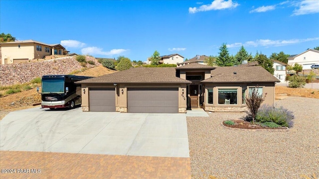 view of front of property with stucco siding, stone siding, driveway, and an attached garage