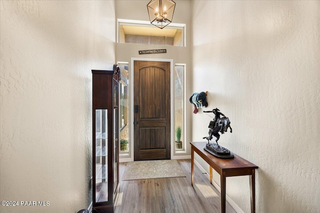 entrance foyer featuring a chandelier, baseboards, a textured wall, and wood finished floors