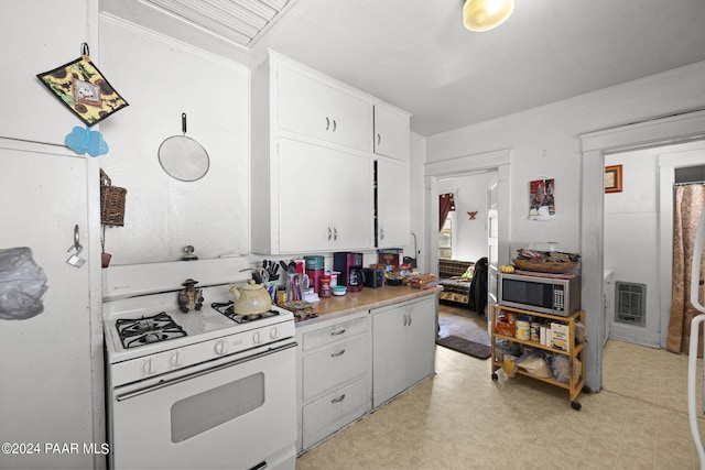 kitchen with white cabinetry, white range with gas cooktop, and heating unit