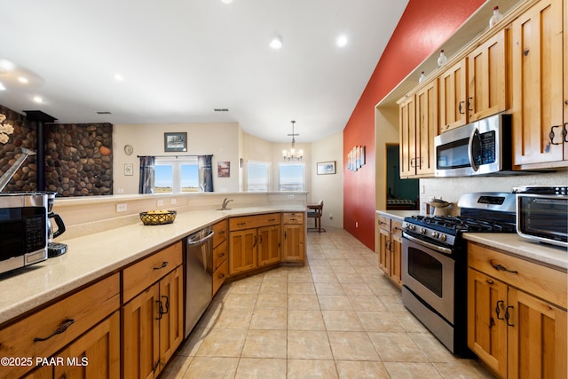 kitchen featuring hanging light fixtures, appliances with stainless steel finishes, light tile patterned floors, a notable chandelier, and decorative backsplash