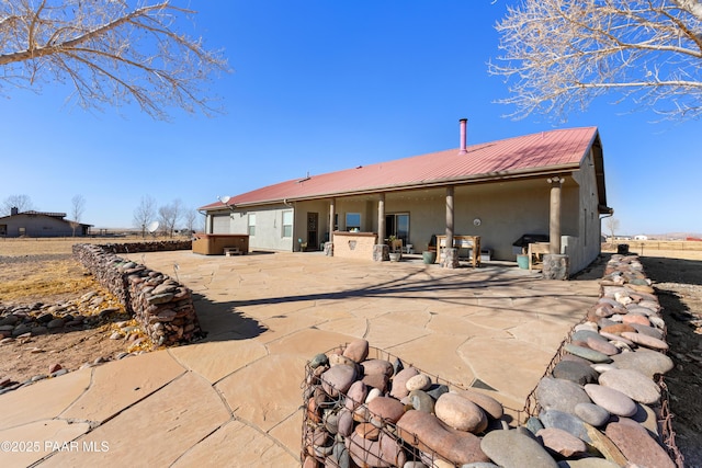 rear view of property with a patio area and a jacuzzi