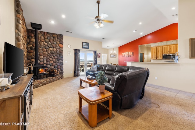 carpeted living room with ceiling fan, vaulted ceiling, and a wood stove