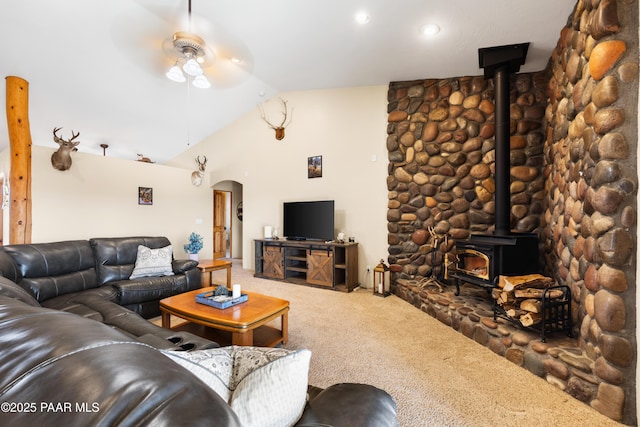 living room with a wood stove, ceiling fan, carpet floors, and lofted ceiling