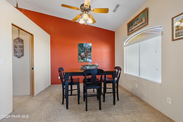 dining space with ceiling fan, light carpet, and lofted ceiling