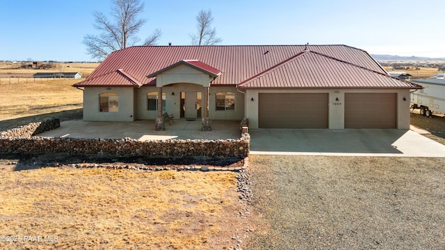 view of front of house with a garage, metal roof, driveway, and stucco siding