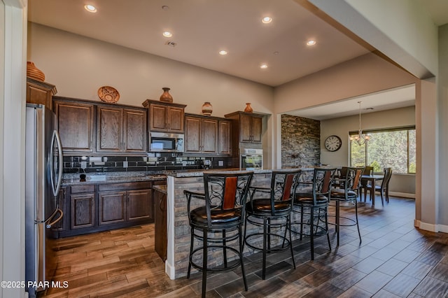 892 Canyon Breeze Ct, Prescott, AZ 86303 - kitchen with dark wood-style flooring, dark brown cabinetry, a kitchen breakfast bar, backsplash, and stainless steel appliances