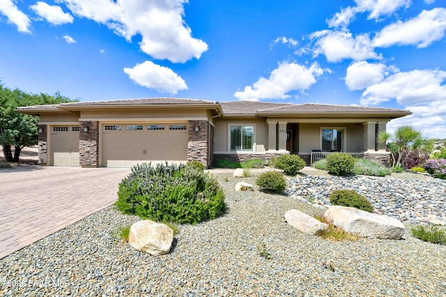 892 Canyon Breeze Ct, Prescott, AZ 86303 - prairie-style house featuring a garage, covered porch, stone siding, decorative driveway, and stucco siding