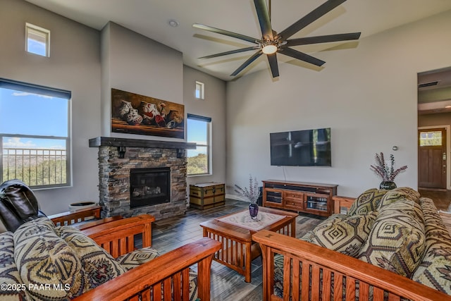 892 Canyon Breeze Ct, Prescott, AZ 86303 - living area with ceiling fan, a stone fireplace, visible vents, a towering ceiling, and wood finished floors