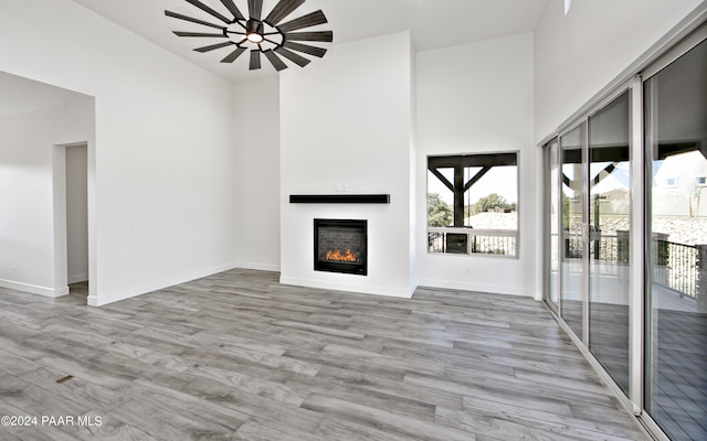 unfurnished living room featuring light hardwood / wood-style flooring and a high ceiling