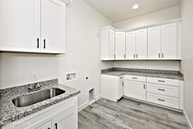 laundry area featuring sink, electric dryer hookup, hookup for a washing machine, cabinets, and light hardwood / wood-style floors