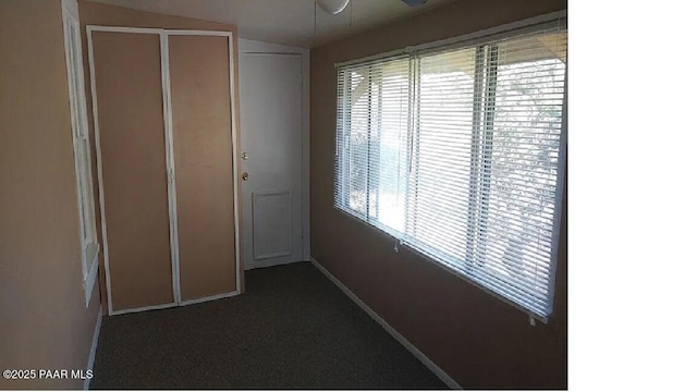 hallway featuring lofted ceiling and dark carpet