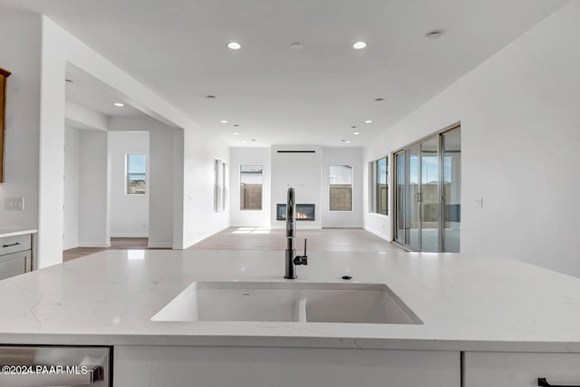 kitchen featuring sink, light stone countertops, and dishwasher