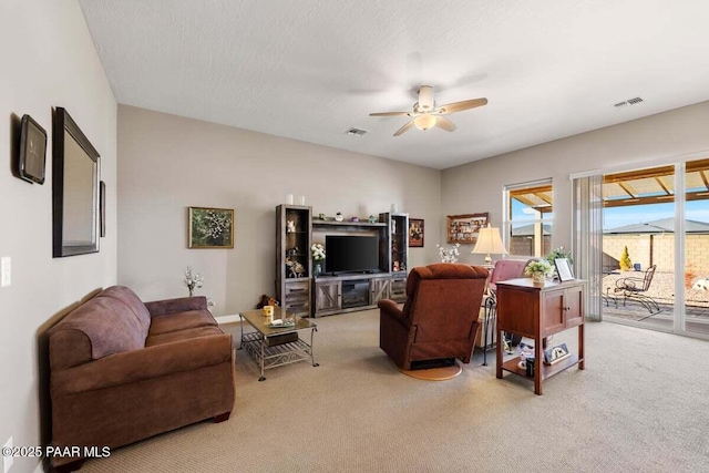 carpeted living room featuring a textured ceiling and ceiling fan