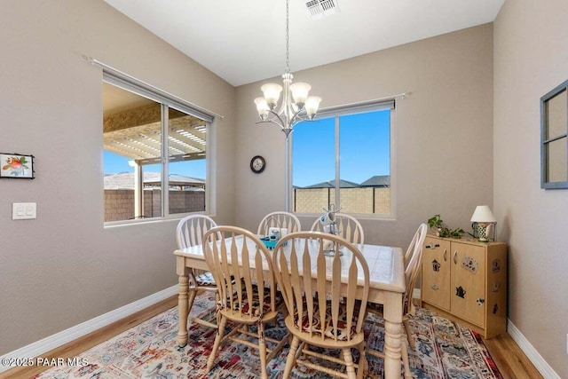 dining room with hardwood / wood-style flooring, a wealth of natural light, and a notable chandelier