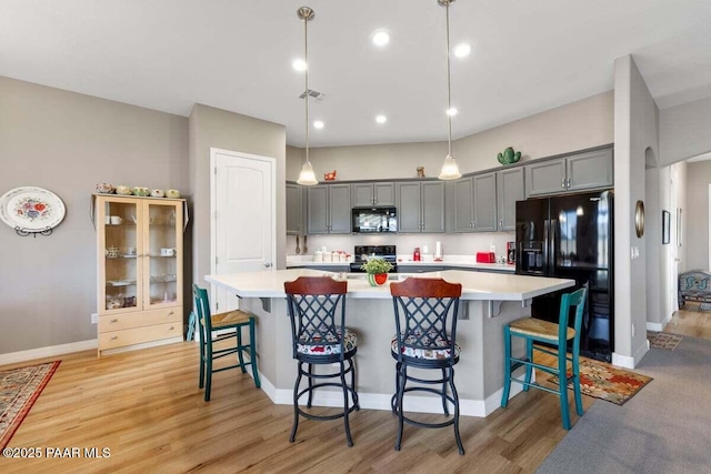 kitchen featuring gray cabinetry, decorative light fixtures, black appliances, and a breakfast bar