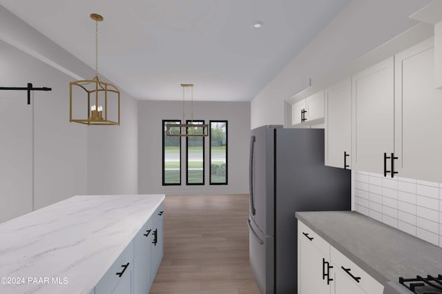 kitchen featuring light stone countertops, decorative light fixtures, a notable chandelier, light hardwood / wood-style floors, and white cabinetry