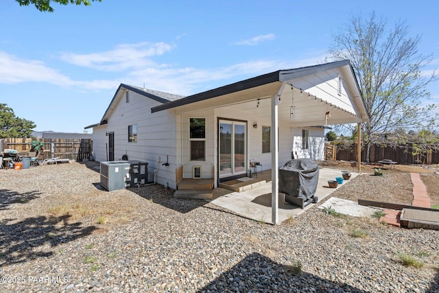 rear view of house featuring central AC unit, a fenced backyard, and a patio area