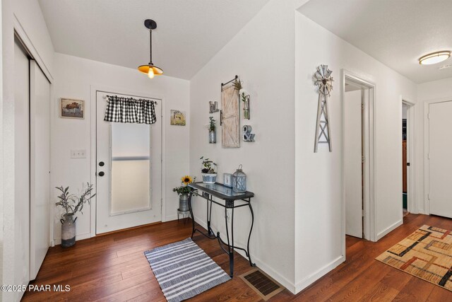 foyer featuring baseboards, visible vents, and wood finished floors