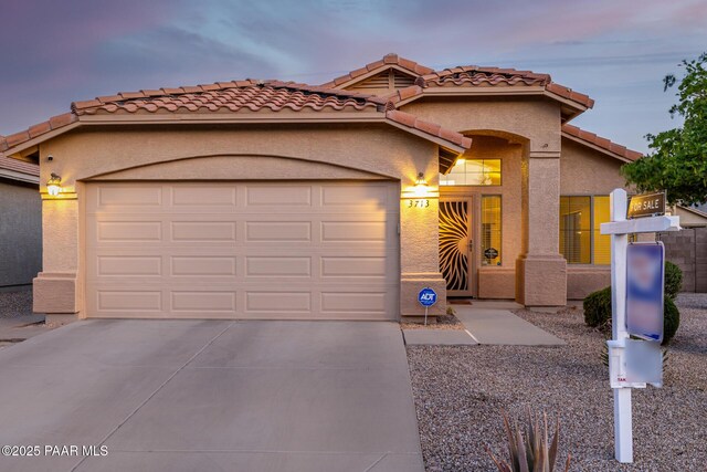 3713 W Nancy Ln, Phoenix, AZ 85041 - mediterranean / spanish-style home featuring an attached garage, concrete driveway, a tile roof, and stucco siding