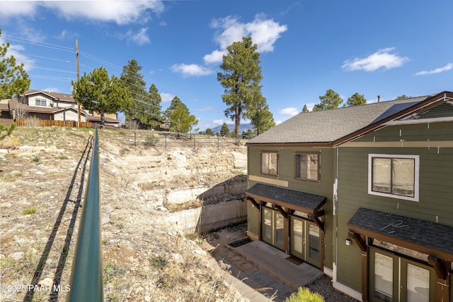 exterior space with fence and a shingled roof