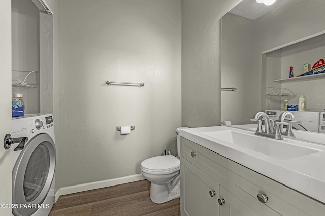 bathroom with wood finished floors, washer / dryer, toilet, vanity, and baseboards