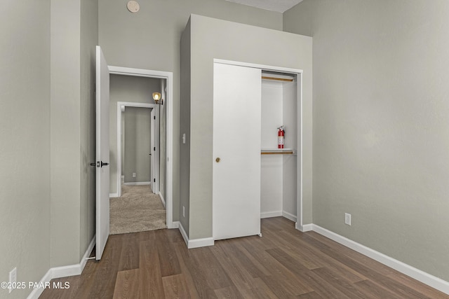 unfurnished bedroom with dark wood-style floors, baseboards, and a closet