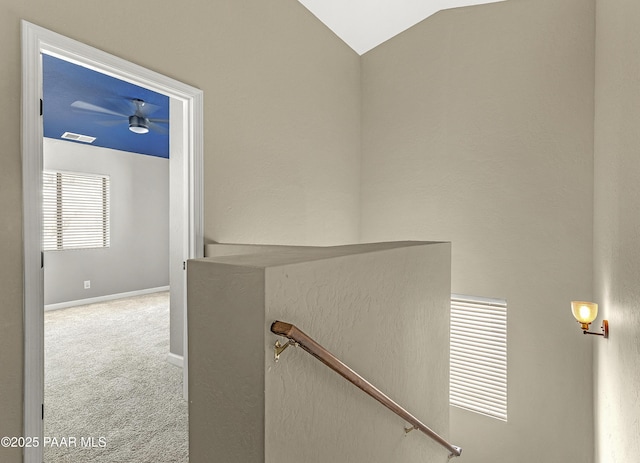 hall featuring vaulted ceiling, an upstairs landing, carpet flooring, baseboards, and visible vents