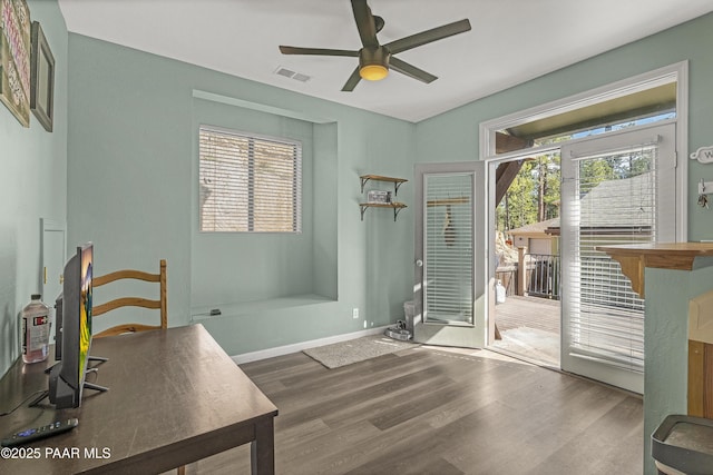 doorway with a ceiling fan, visible vents, wood finished floors, and baseboards
