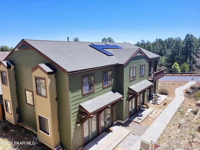 view of front of house featuring solar panels and roof with shingles