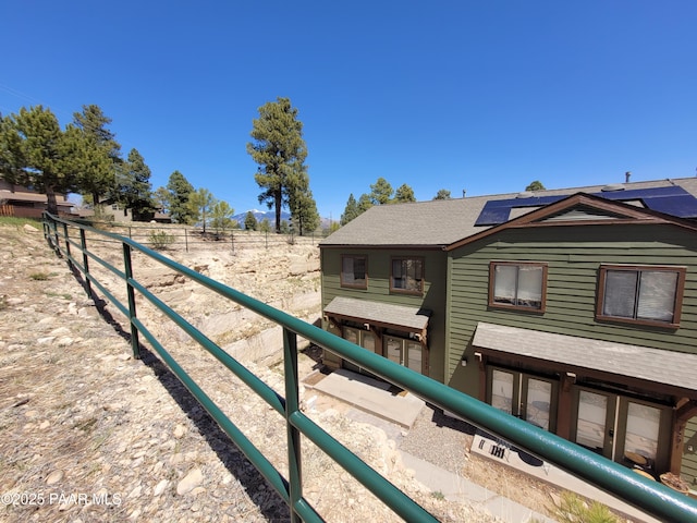exterior space with roof mounted solar panels and roof with shingles