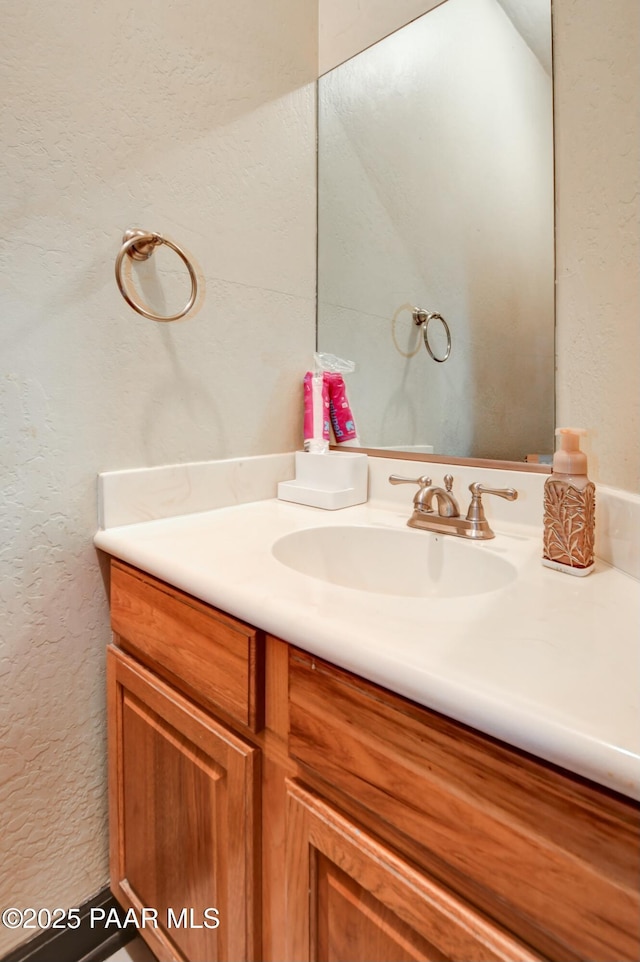 bathroom with a textured wall and vanity