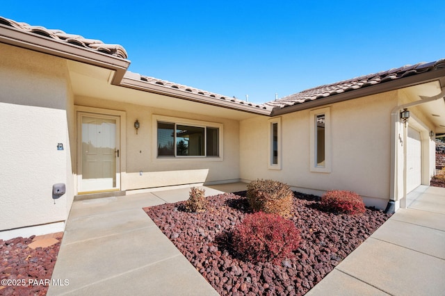 view of exterior entry featuring a garage and a patio