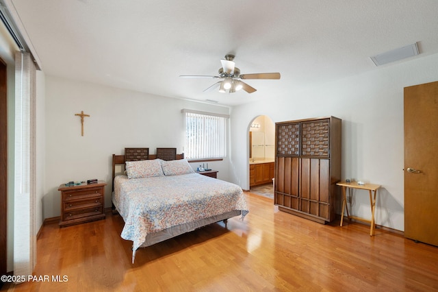 bedroom with hardwood / wood-style flooring, ensuite bathroom, and ceiling fan