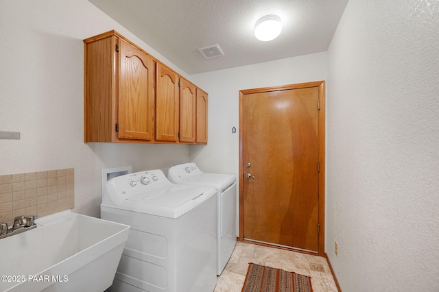 laundry area with separate washer and dryer, sink, cabinets, and a textured ceiling