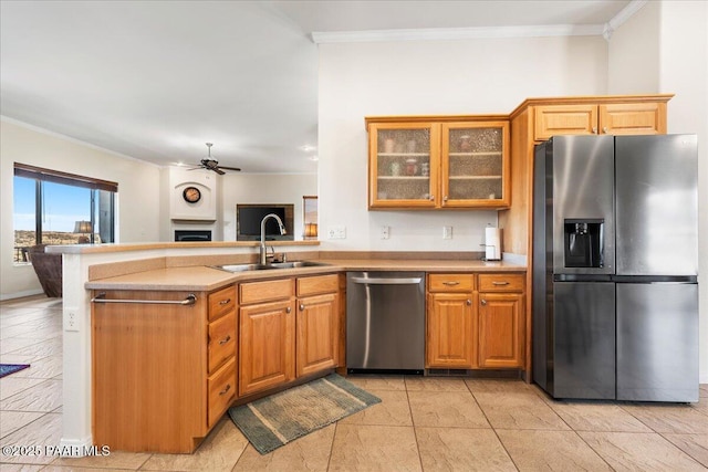 kitchen with ceiling fan, kitchen peninsula, sink, stainless steel appliances, and ornamental molding