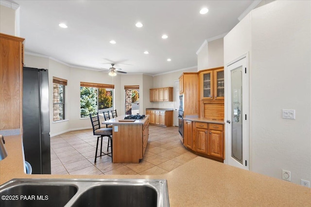 kitchen with ceiling fan, a center island, a kitchen bar, crown molding, and stainless steel appliances