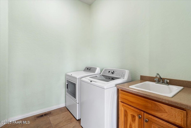 washroom featuring sink, separate washer and dryer, and cabinets