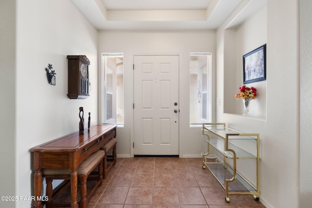 foyer entrance with a tray ceiling and light tile patterned floors