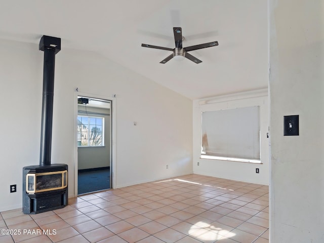 unfurnished living room featuring ceiling fan, light tile patterned floors, vaulted ceiling, and a wood stove