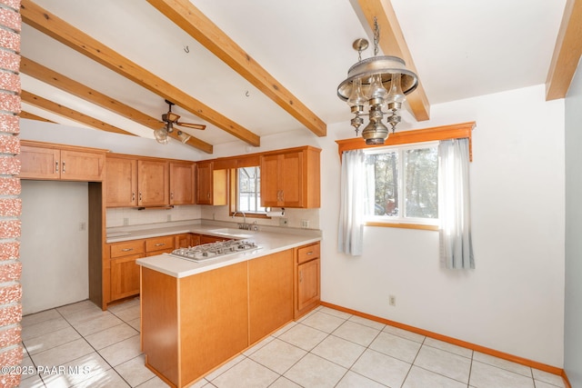 kitchen with pendant lighting, sink, beam ceiling, kitchen peninsula, and stainless steel gas stovetop