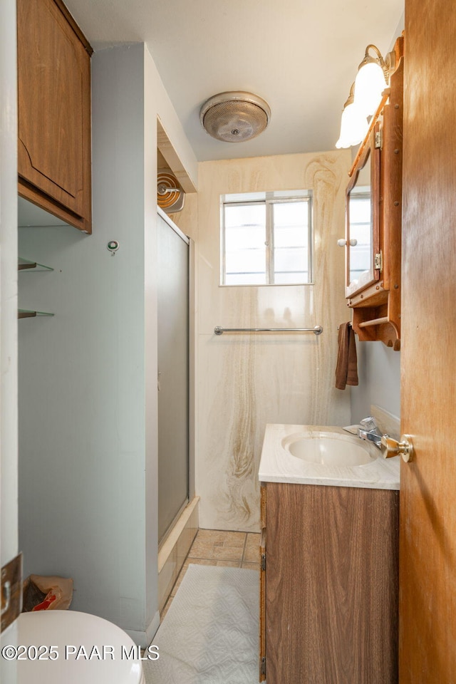 bathroom featuring vanity, an enclosed shower, and toilet