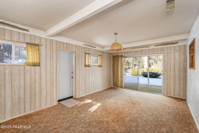 interior space featuring a textured ceiling, beamed ceiling, and a healthy amount of sunlight