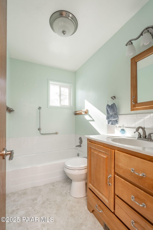 bathroom featuring vanity, a tub to relax in, and toilet