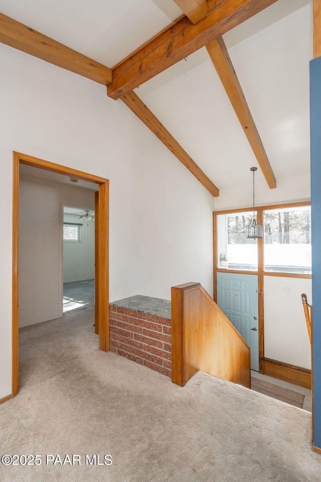 carpeted entryway with vaulted ceiling with beams