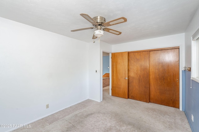 unfurnished bedroom featuring ceiling fan, light colored carpet, and a closet