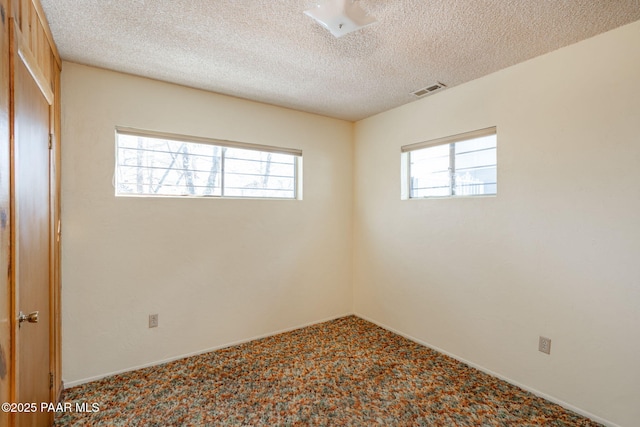 carpeted empty room featuring a textured ceiling